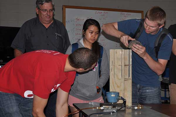 Micah Bolin, Sydney Gard and Ryan Hanousek prepare their device for the competition at the Rapid Design Challenge as Roger Hoy, professor of biological systems engineering, looks on.