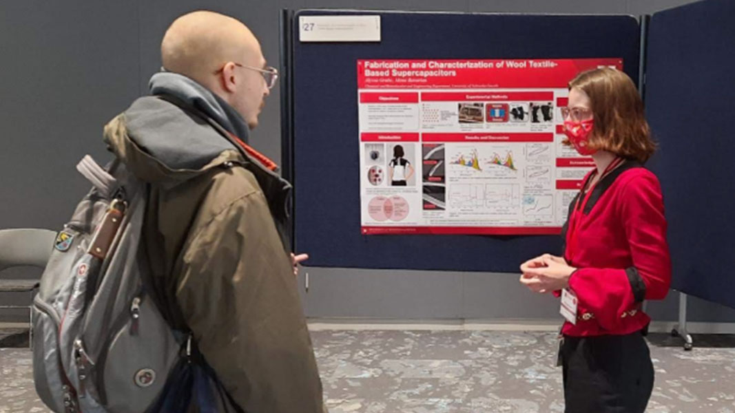 Alyssa presenting their poster at the Graduate Student Symposium 2023.