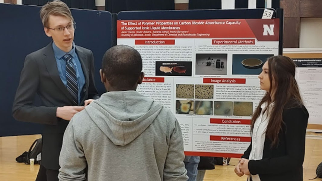 Jarod and Taylor presenting their poster to an audience member. 