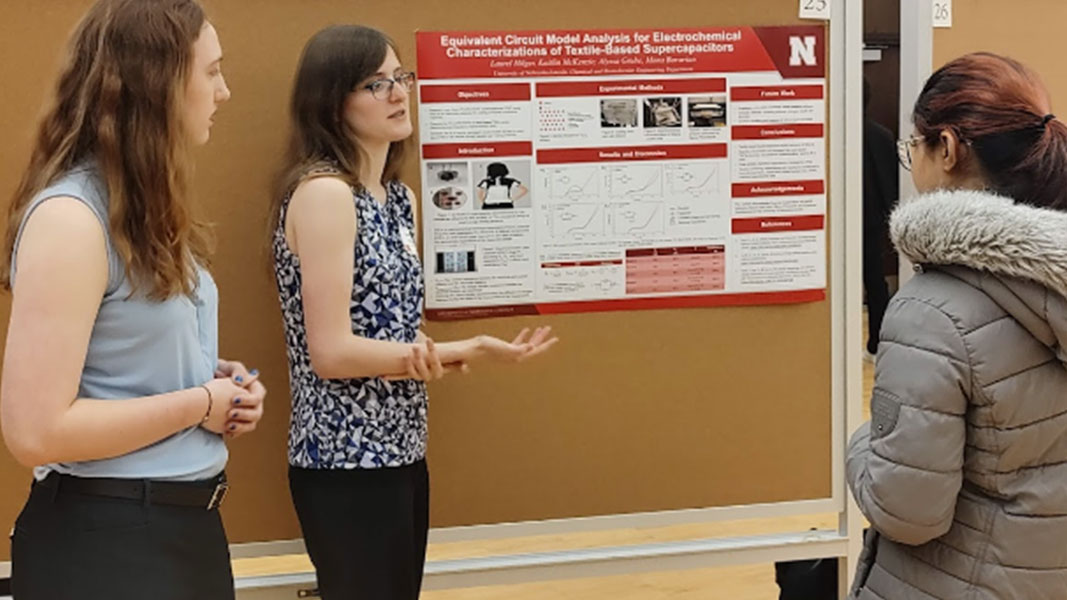 Kate and Laurel presenting their poster to an audience member.