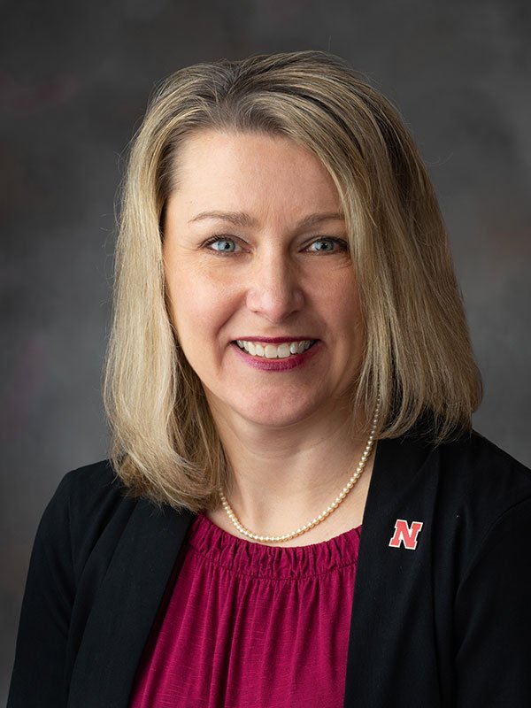 Photo of Jana Burns - black jacket, red shirt, blond hair