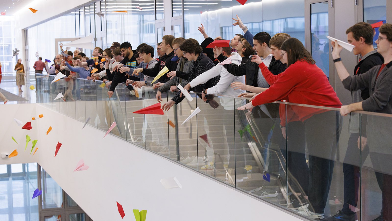 Students in Kiewit Hall throw paper airplanes off a landing