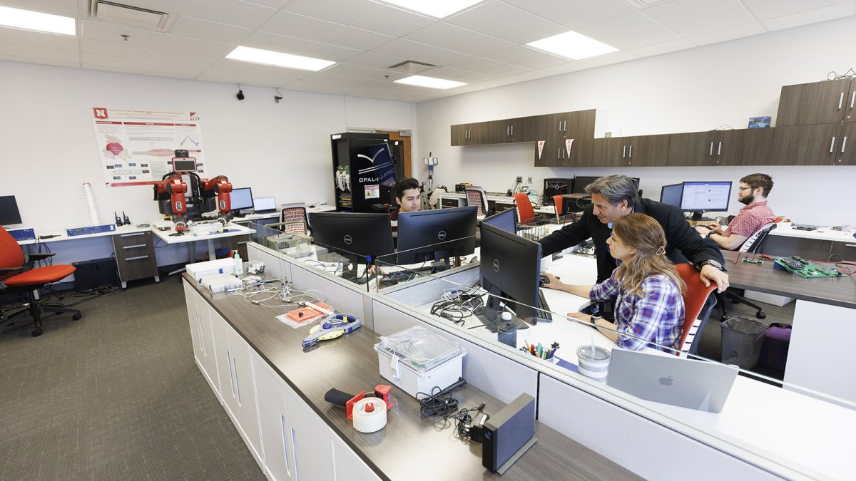 Students and a faculty member work in a lab, looking at computer screens