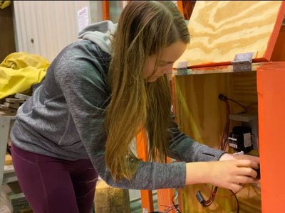 A member of Engineers without Borders working with some wires.