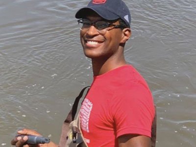 Seth Caines (Biological Systems Engineering student) standing in lake water doing a test.